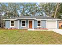 Charming one-story home with a fresh blue exterior, a well-manicured lawn, and a gray roof at 13374 Sw 112 St, Dunnellon, FL 34432