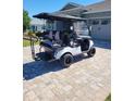 White golf cart with black seats is parked on a brick driveway in front of a home with a garage at 9617 Sw 102Nd Ter, Ocala, FL 34481