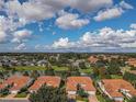 Picturesque aerial view featuring homes with red tile roofs nestled around a scenic lake with a fountain at 5162 Harbour Dr, Oxford, FL 34484