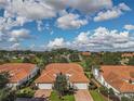 Beautiful aerial view of homes with Spanish tile roofs, well-manicured lawns, and a serene pond at 5162 Harbour Dr, Oxford, FL 34484