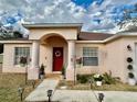 Attractive home entrance with a red front door, decorative wreath, and manicured landscaping at 8335 Se 162Nd Pl, Summerfield, FL 34491