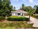 Charming single-story home featuring a manicured lawn with trees and an American flag at 12805 Sw 64Th Ln, Ocala, FL 34481