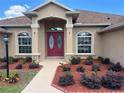 Inviting front entrance with red double doors, manicured landscaping, and a well-lit walkway at 10923 Sw 38Th Ave, Ocala, FL 34476