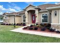 Inviting facade with a vibrant red door, stone accents, and beautifully landscaped front yard at 10923 Sw 38Th Ave, Ocala, FL 34476