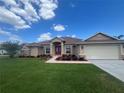 Charming home with a lush lawn, red double door, and a convenient two-car garage at 10923 Sw 38Th Ave, Ocala, FL 34476