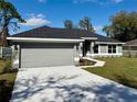 Charming one-story home with a well-manicured lawn, showcasing the facade, driveway, and garage at 9869 Se 157Th Ln, Summerfield, FL 34491