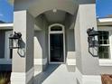 Close-up of front door with decorative columns, black hardware, and exterior lighting fixtures at 9869 Se 157Th Ln, Summerfield, FL 34491