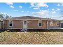 Back of home featuring neutral siding, functional door, and adjacent yard at 33 Pecan Pass Run, Ocala, FL 34472
