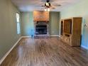Spacious living room featuring a brick fireplace, wood floors, and a wooden entertainment center at 727 Ne 130Th Ter, Silver Springs, FL 34488