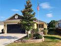 One-story house with a two-car garage, landscaping, and American flag at 9873 Sw 99Th Loop, Ocala, FL 34481