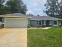 Inviting one-story home featuring a well-manicured lawn and a convenient two-car garage at 15067 Se 61St Ct, Summerfield, FL 34491