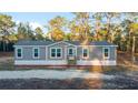 Inviting single-story home with gray siding and a welcoming front porch, nestled among lush trees at 11837 Se 165 Ave, Ocklawaha, FL 32179