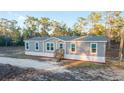 Inviting single-story home featuring a welcoming front porch, complemented by beautiful surroundings at 11837 Se 165 Ave, Ocklawaha, FL 32179