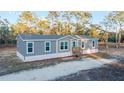 Single-story home with a charming front porch and well-manicured lawn, surrounded by lush greenery at 11837 Se 165 Ave, Ocklawaha, FL 32179