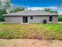 Rear view of a single-story home with a sliding glass door and modest backyard at 24780 Nw Hillsdale Ave, Dunnellon, FL 34431