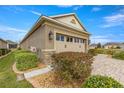 Tan one-story house with side yard landscaping and two-car garage at 9870 Sw 99Th Loop, Ocala, FL 34481