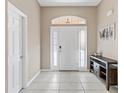Bright foyer with neutral tile flooring, transom window, and decorative console table at 10927 Se 168Th Loop, Summerfield, FL 34491