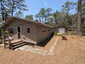 View of the home, stone walkway, and detached garage surrounded by mature trees and natural landscaping at 14830 Se 61St Street Rd, Ocklawaha, FL 32179