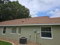Back exterior with light green siding, a brown roof, and an efficient HVAC system at 10975 Sw 69Th Cir, Ocala, FL 34476