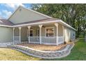 Green house with white trim, a covered porch and landscaped yard at 10975 Sw 69Th Cir, Ocala, FL 34476