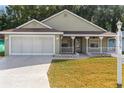 House exterior featuring a covered porch and a two-car garage at 10975 Sw 69Th Cir, Ocala, FL 34476