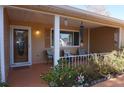 Inviting front porch featuring comfortable seating, decorative wind chimes, and colorful potted plants at 10886 Sw 90Th Ter, Ocala, FL 34481