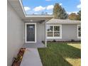 A gray exterior home entrance featuring a walkway, well-kept lawn, and a charming dark front door at 176 Pine Crse, Ocala, FL 34472