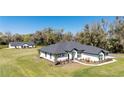 Single-story home boasts a dark gray roof, white siding, black trim, and inviting curb appeal at 1725 W Hwy 329, Citra, FL 32113