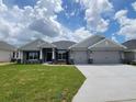 Beautiful single Gathering home featuring a 3-car garage and well-maintained lawn with decorative stone accents at 8309 Sw 58Th Ave, Ocala, FL 34476