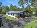 Exterior view of a modern horse barn featuring an open-air lounge area and attached parking at 965 Nw 73Rd Ter, Ocala, FL 34482