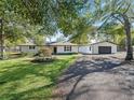 Charming home exterior with lush lawn, mature trees, and blacktop driveway leading to detached garage at 965 Nw 73Rd Ter, Ocala, FL 34482