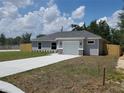 Charming single-story home with a gray exterior, manicured lawn, and a concrete driveway leading to a one-car garage at 13441 Sw 113Th Pl, Dunnellon, FL 34432