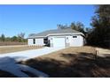 One-story house with gray siding, white garage door, and a stone accent at 13441 Sw 113Th Pl, Dunnellon, FL 34432