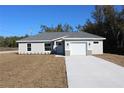 One-story house with gray siding, white garage door, and a stone accent at 13441 Sw 113Th Pl, Dunnellon, FL 34432