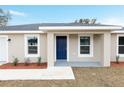 A single-story home with a neutral exterior, blue front door, white trim, and a manicured lawn at 1877 Sw 150 Ct, Ocala, FL 34481