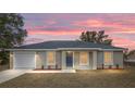 A single-story home featuring a blue front door, white garage door, well-manicured lawn at sunset at 1877 Sw 150 Ct, Ocala, FL 34481