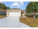 Inviting one-story home featuring a wide driveway, a two-car garage, and lovely landscaping at 9464 Se 132Nd Loop, Summerfield, FL 34491