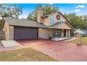 Two-story house with brick and beige siding, a red driveway, and landscaping at 5370 Se 28Th St, Ocala, FL 34480