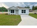 Newly built home with a light blue exterior, grassy lawn, and driveway at 6568 Se 108Th Ln, Belleview, FL 34420