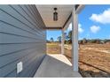 Covered porch with gray siding, white columns, and a light fixture at 3496 Sw 149Th Ct, Ocala, FL 34481