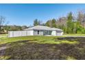 Side view of a newly built home with light teal exterior and a white vinyl fence at 14462 Se 28Th Ct, Summerfield, FL 34491