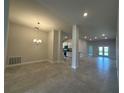 Open-concept living room with tile flooring leading to a modern kitchen and bright patio doors at 4445 Sw 90Th Pl, Ocala, FL 34476