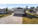 Two-car garage with paver driveway and landscaped yard at 10282 Sw 99Th Ln, Ocala, FL 34481