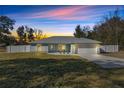 Charming one-story house with light blue exterior, white garage door, and well-manicured lawn at dusk at 14366 Se 27Th Ct, Summerfield, FL 34491