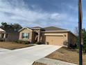 Tan house with stone accents, two-car garage, and landscaped yard at 6365 Sw 88Th Loop, Ocala, FL 34476