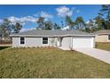 Newly built single-story house featuring gray siding, a white garage door, and a neat lawn at 13351 Sw 83Rd Cir, Ocala, FL 34473