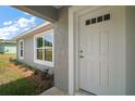 Close-up of the front entrance featuring a white door with decorative glass and manicured landscaping at 174 Pine Crse, Ocala, FL 34472