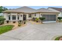 Tan house with screened garage and manicured landscaping at 2117 Sansores St, The Villages, FL 32159