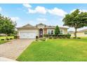 Charming single-story home featuring a well-manicured lawn, brick driveway, and tasteful landscaping under a blue sky at 6407 Sw 45Th Ave, Ocala, FL 34474