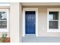 Close-up of a stylish blue front door with white trim, complemented by manicured landscaping and fresh exterior paint at 14977 Sw 21St Pl, Ocala, FL 34481